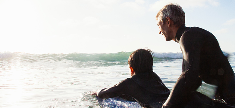 父亲和儿子在一个阳光明媚的日子里冲浪